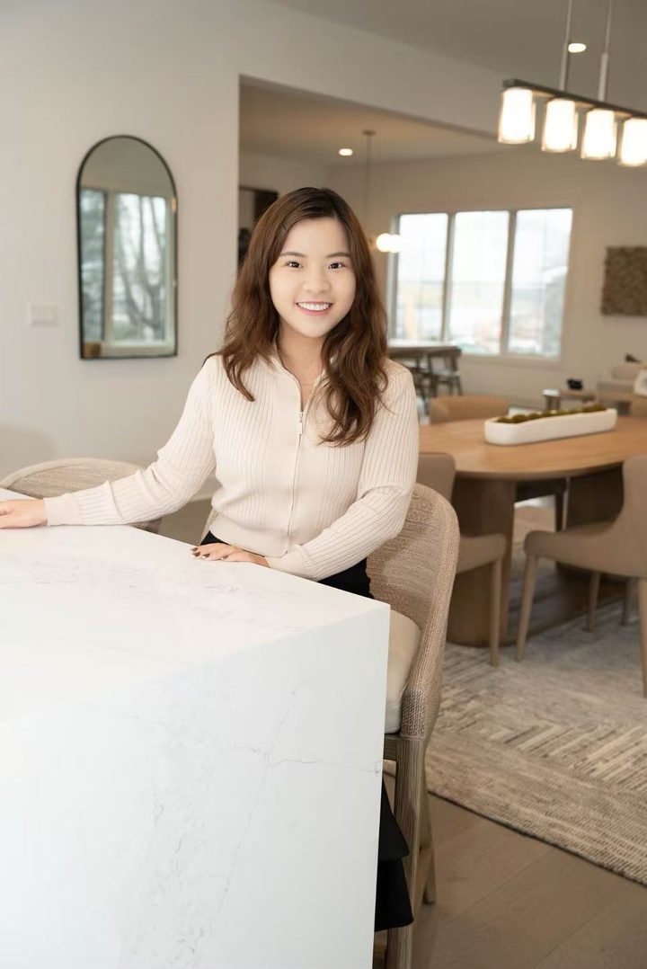 Vivikin Wen seated at a white marble kitchen island in a bright, modern home